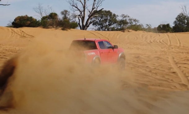 Ranger Raptor driving through sand rear view