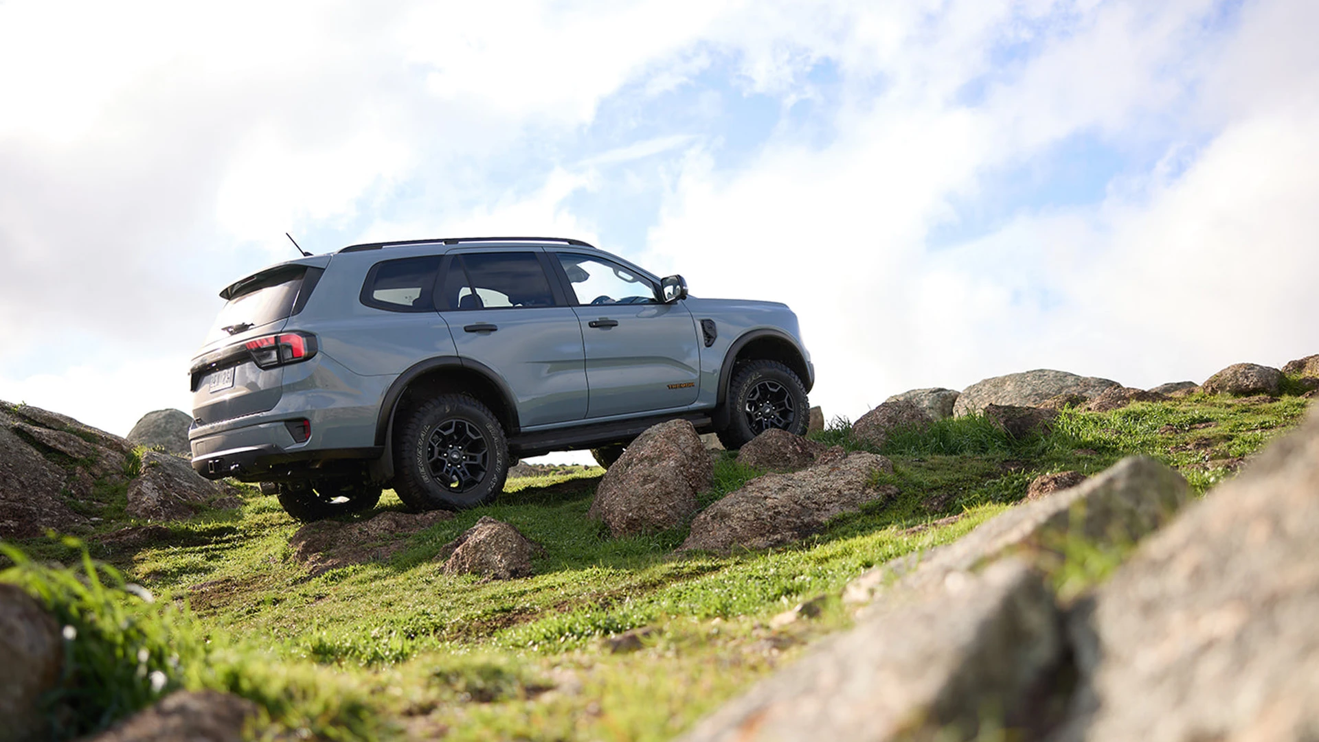Grey SUV driving over rocks