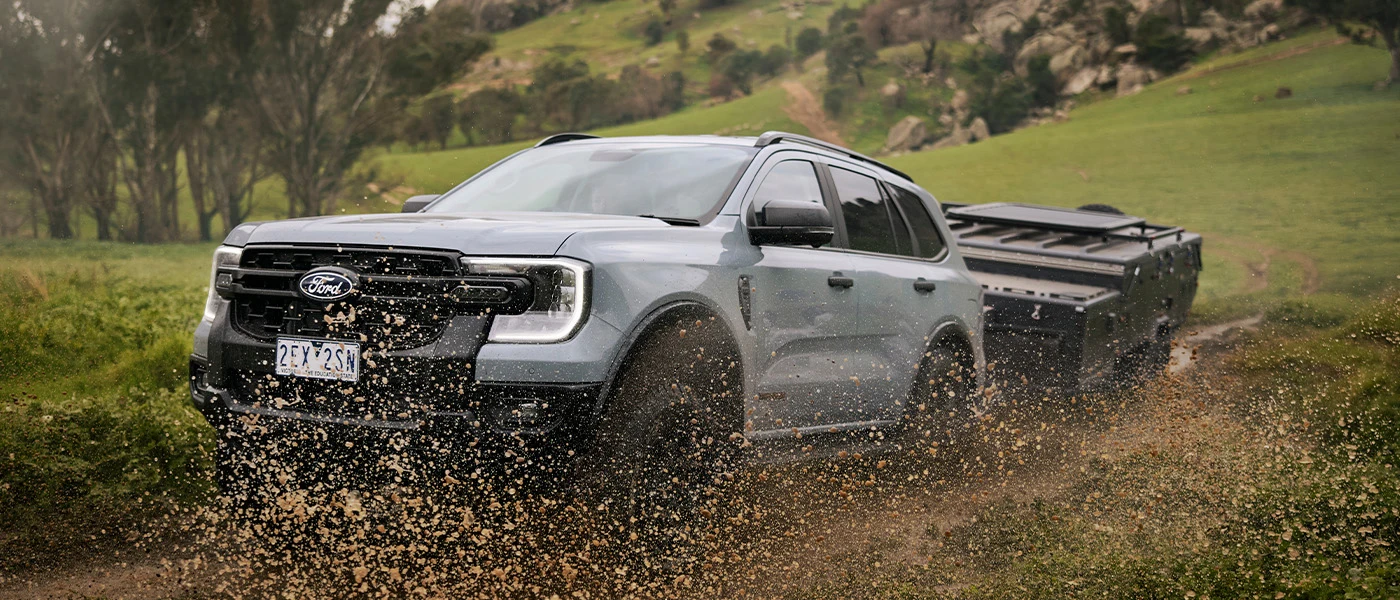 SUV towing trailer through mud